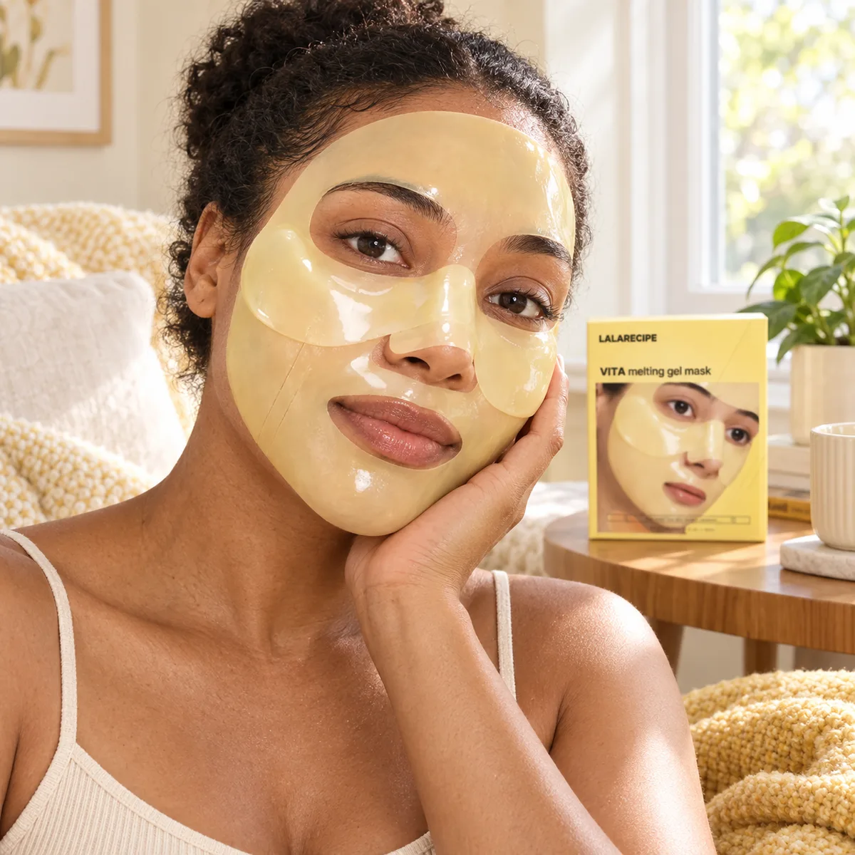 Woman wearing a pale yellow Vita hydrogel mask, with a Vita Melting Gel Mask box beside her